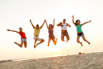 Image showing smiling friends dancing and jumping on beach