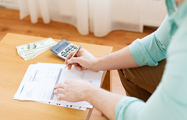 Image showing close up of man counting money and making notes