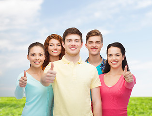 Image showing group of smiling teenagers over blue sky and grass