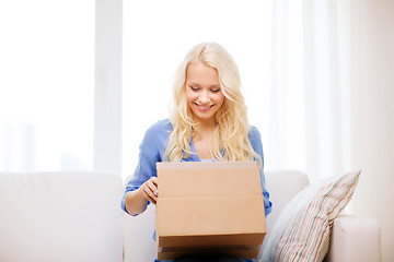 Image showing smiling young woman opening cardboard box