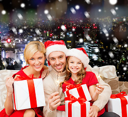 Image showing happy family in santa helper hats with gift boxes