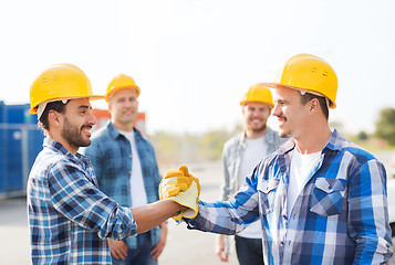 Image showing group of smiling builders shaking hands outdoors