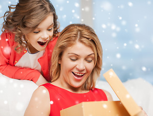 Image showing smiling mother and daughter with gift box at home