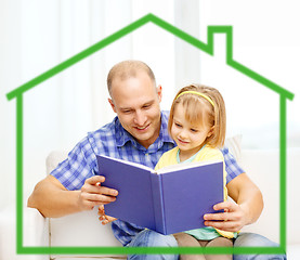 Image showing smiling father and daughter reading book at home