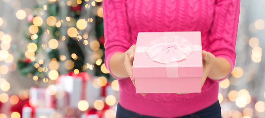 Image showing close up of woman in pink sweater holding gift box