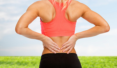 Image showing close up of sporty woman touching her back