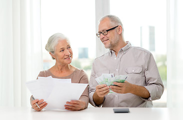 Image showing senior couple with money and calculator at home