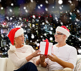 Image showing happy senior couple in santa hats with gift box