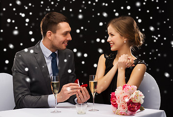 Image showing smiling couple with red gift box at restaurant