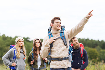 Image showing smiling hikers with backpacks pointing finger