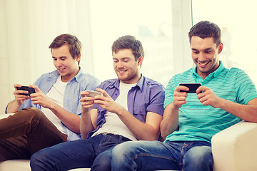 Image showing smiling friends with smartphones at home