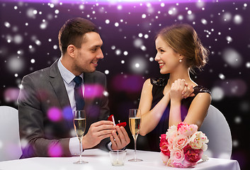 Image showing smiling couple with red gift box at restaurant