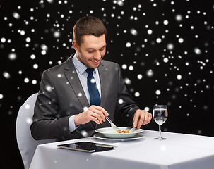 Image showing smiling man with tablet pc eating main course