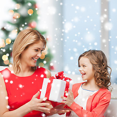 Image showing smiling mother and daughter with gift box at home