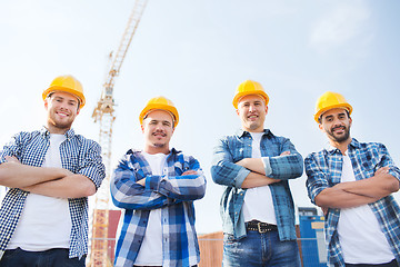 Image showing group of smiling builders in hardhats outdoors