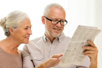 Image showing happy senior couple reading newspaper at home