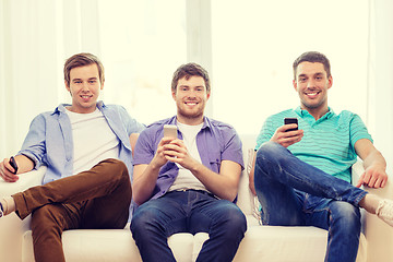 Image showing smiling friends with smartphones at home