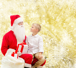 Image showing smiling little boy with santa claus and gifts