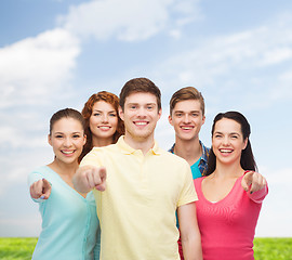 Image showing group of smiling teenagers over blue sky and grass