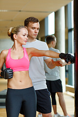 Image showing smiling woman with personal trainer boxing in gym