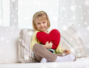 Image showing smiling girl with big red heart sitting on sofa