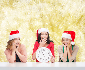 Image showing smiling women in santa helper hats with clock