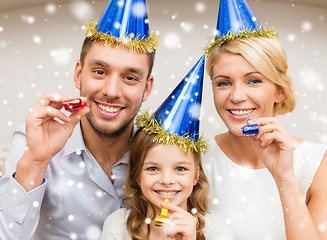 Image showing smiling family in party hats blowing favor horns