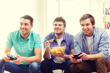 Image showing smiling friends playing video games at home