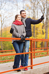 Image showing smiling couple hugging on bridge in autumn park