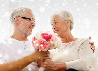Image showing happy senior couple with bunch of flowers at home