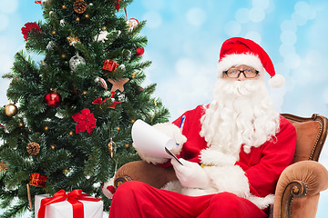 Image showing man in costume of santa claus with notepad