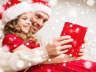 Image showing smiling father and girl in santa hats reading book