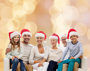 Image showing happy family in santa helper hats sitting on couch