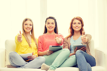 Image showing three smiling teenage girls with tablet pc at home