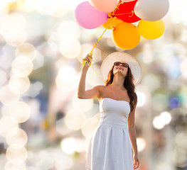 Image showing smiling young woman in sunglasses with balloons