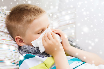 Image showing ill boy blowing nose with tissue at home