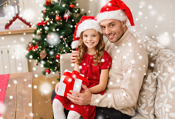 Image showing smiling father and daughter with gift box at home