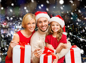 Image showing happy family in santa helper hats with gift boxes