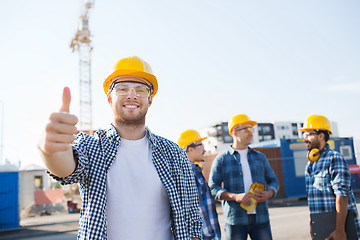 Image showing group of smiling builders in hardhats outdoors