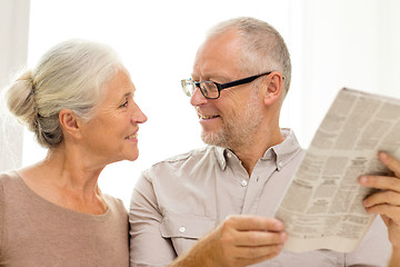 Image showing happy senior couple reading newspaper at home