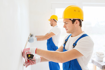 Image showing group of builders with measuring tape indoors