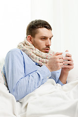 Image showing man in scarf holding cup with hot drink at home