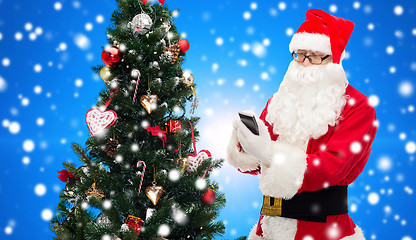 Image showing santa claus with smartphone and christmas tree