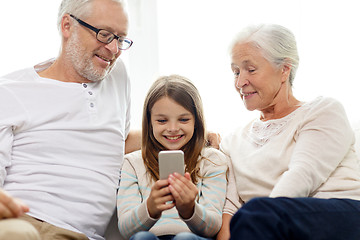 Image showing smiling family with smartphone at home