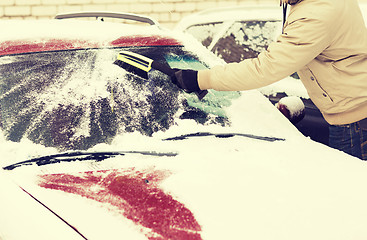 Image showing closeup of man cleaning snow from car