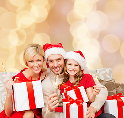 Image showing happy family in santa helper hats with gift boxes