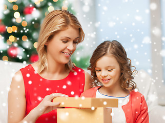 Image showing smiling mother and daughter with gift box at home