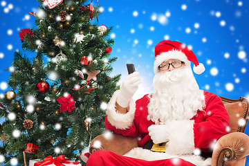 Image showing santa claus with smartphone and christmas tree