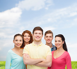 Image showing group of smiling teenagers over blue sky and grass
