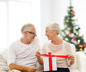 Image showing happy senior couple with gift box at home